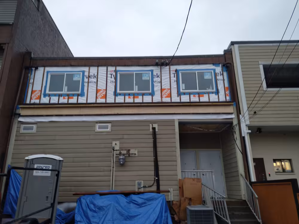 Three second-story windows with Tyvek house wrap and flashing on a building under renovation.
