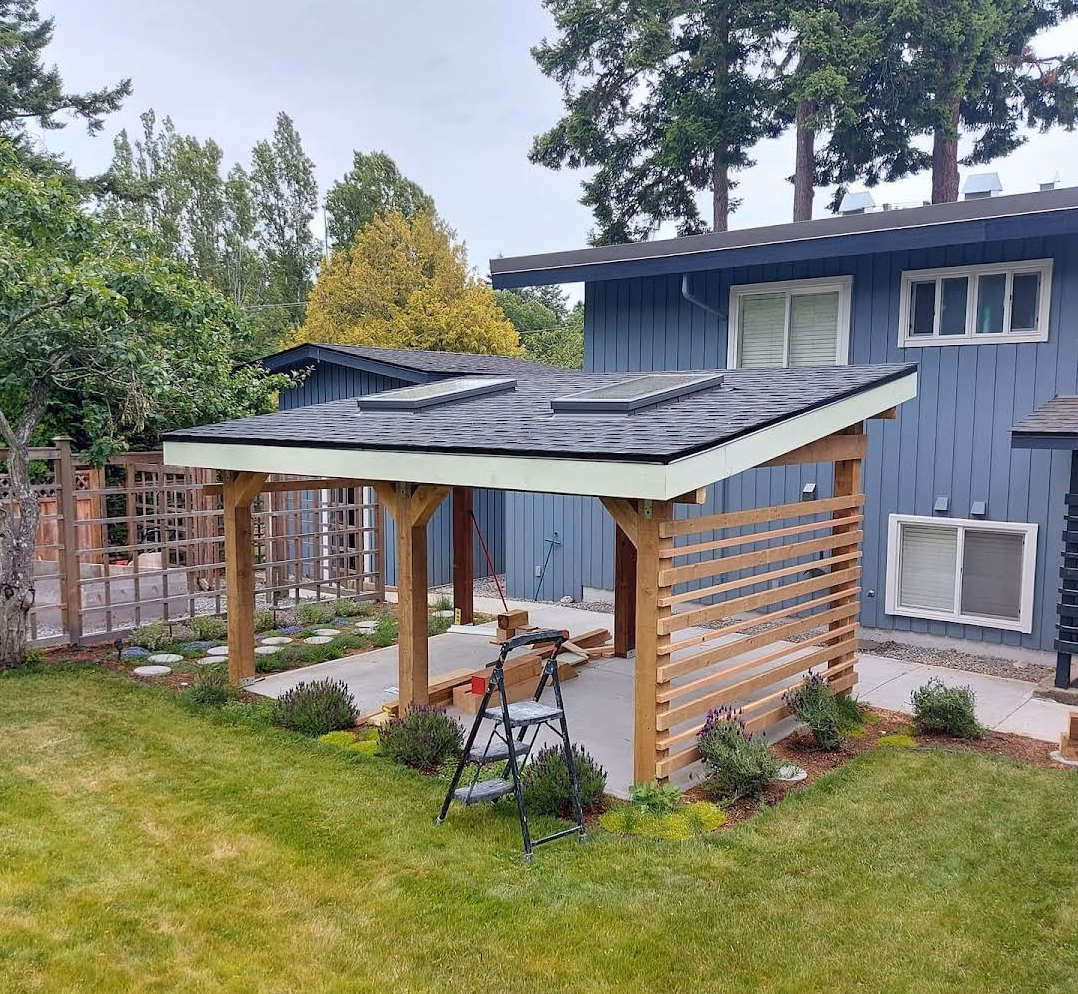 Modern deck gazebo with slatted wood walls, skylights, and a swing bench in a landscaped backyard.