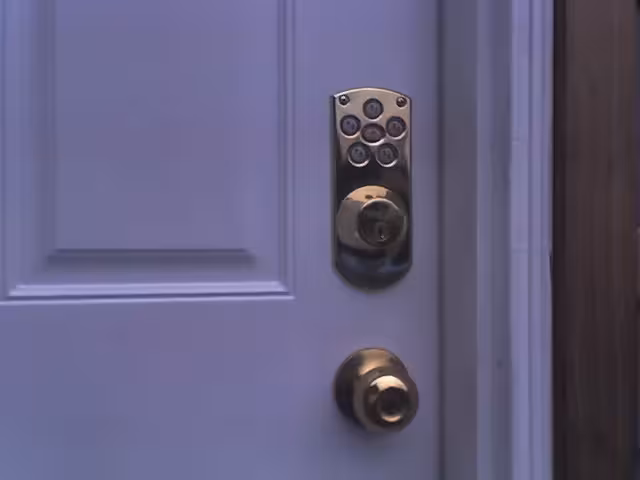 Electronic keypad deadbolt and brass doorknob on a white entry door