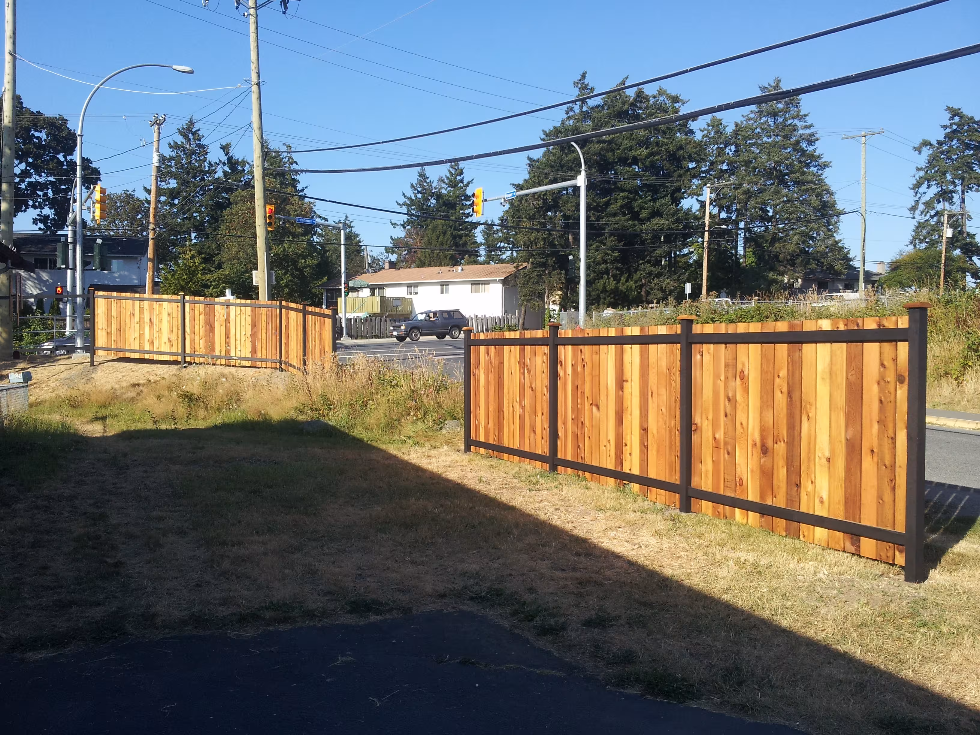 Cedar sectional fence with black metal posts along a suburban street.