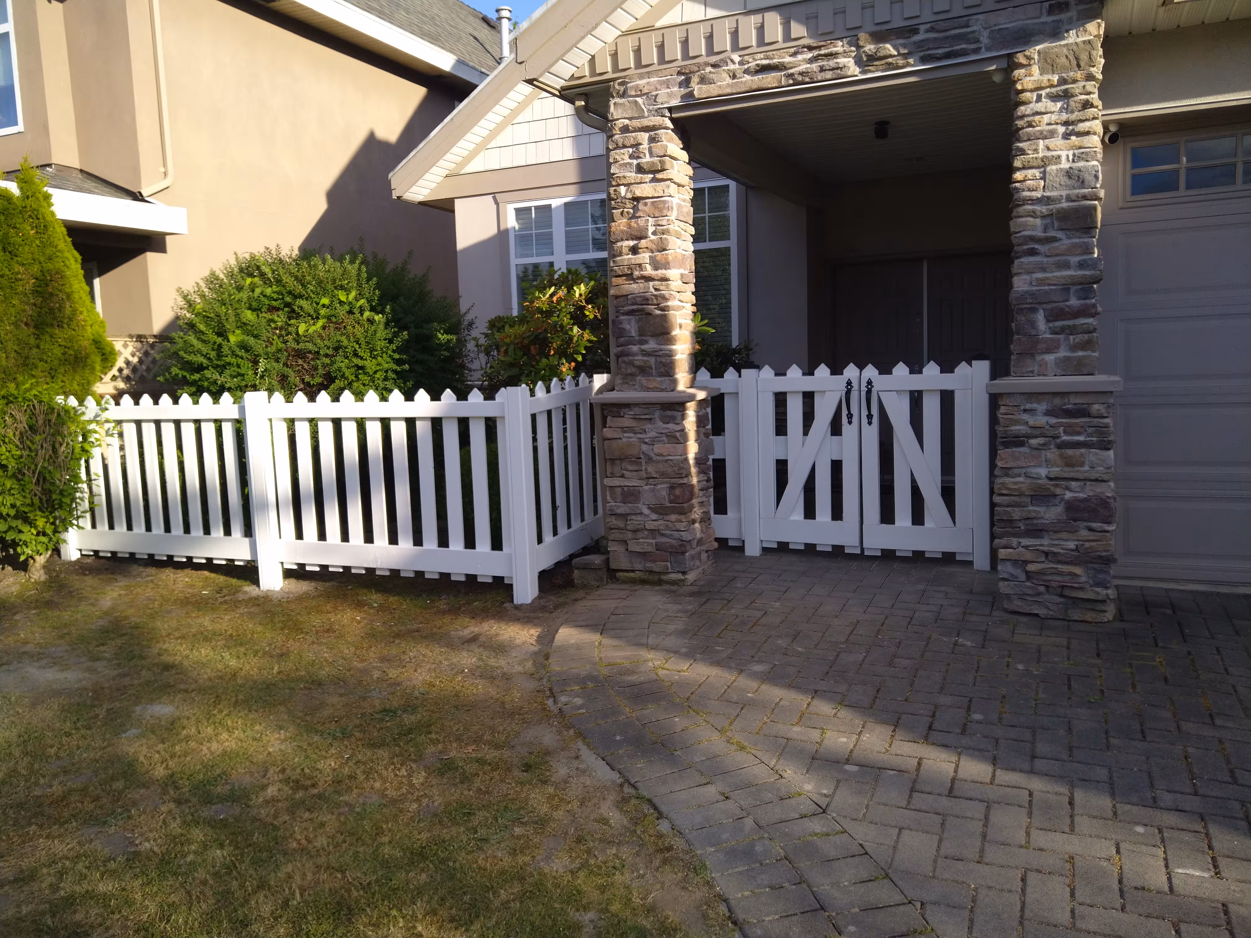 White picket fence and gate around a home's front entry and driveway.
