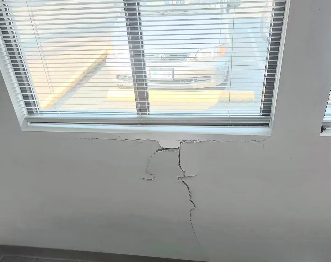 Large crack in interior wall beneath window, before repair.