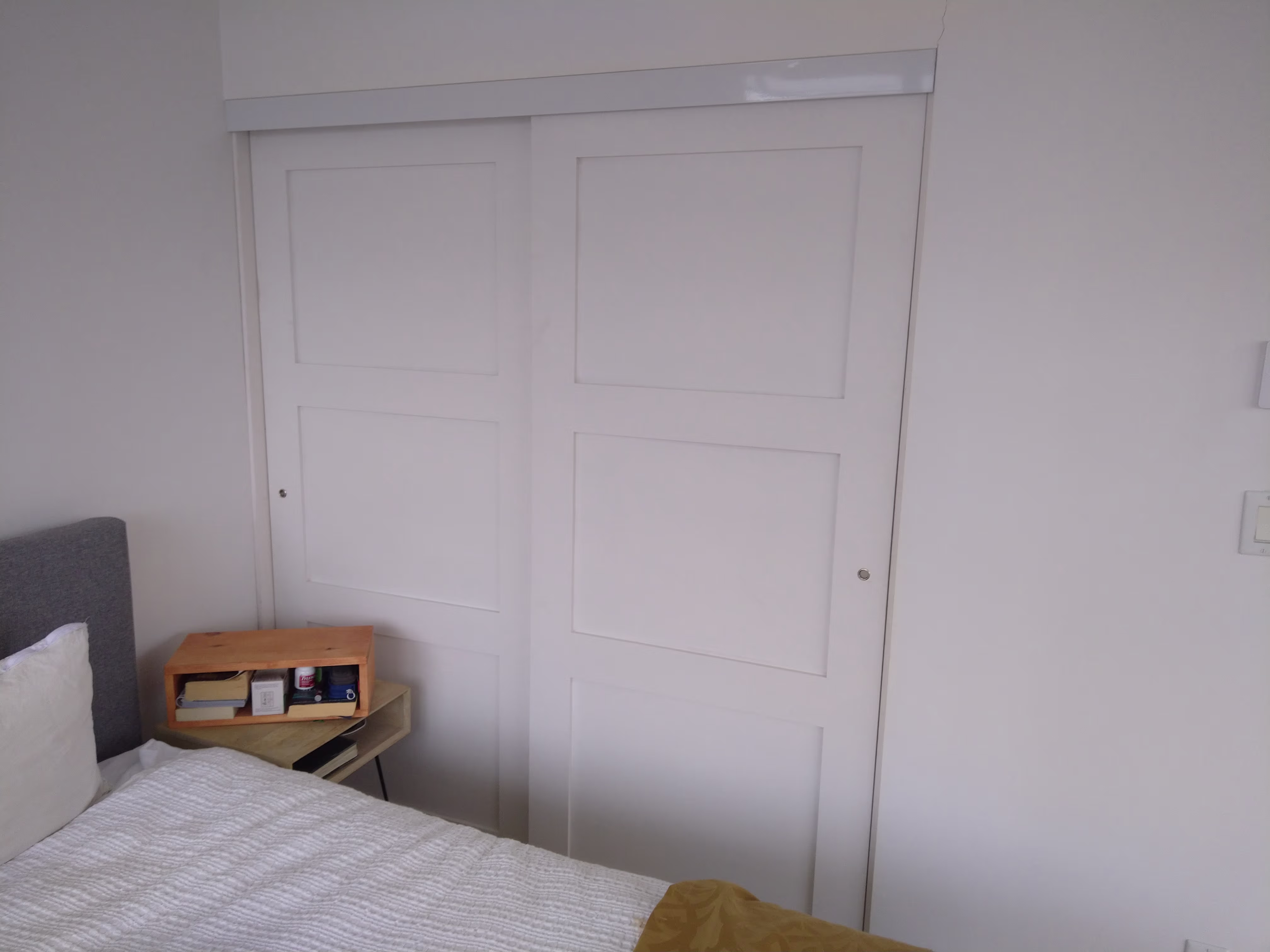 White sliding closet doors with recessed panels in a minimalist bedroom.