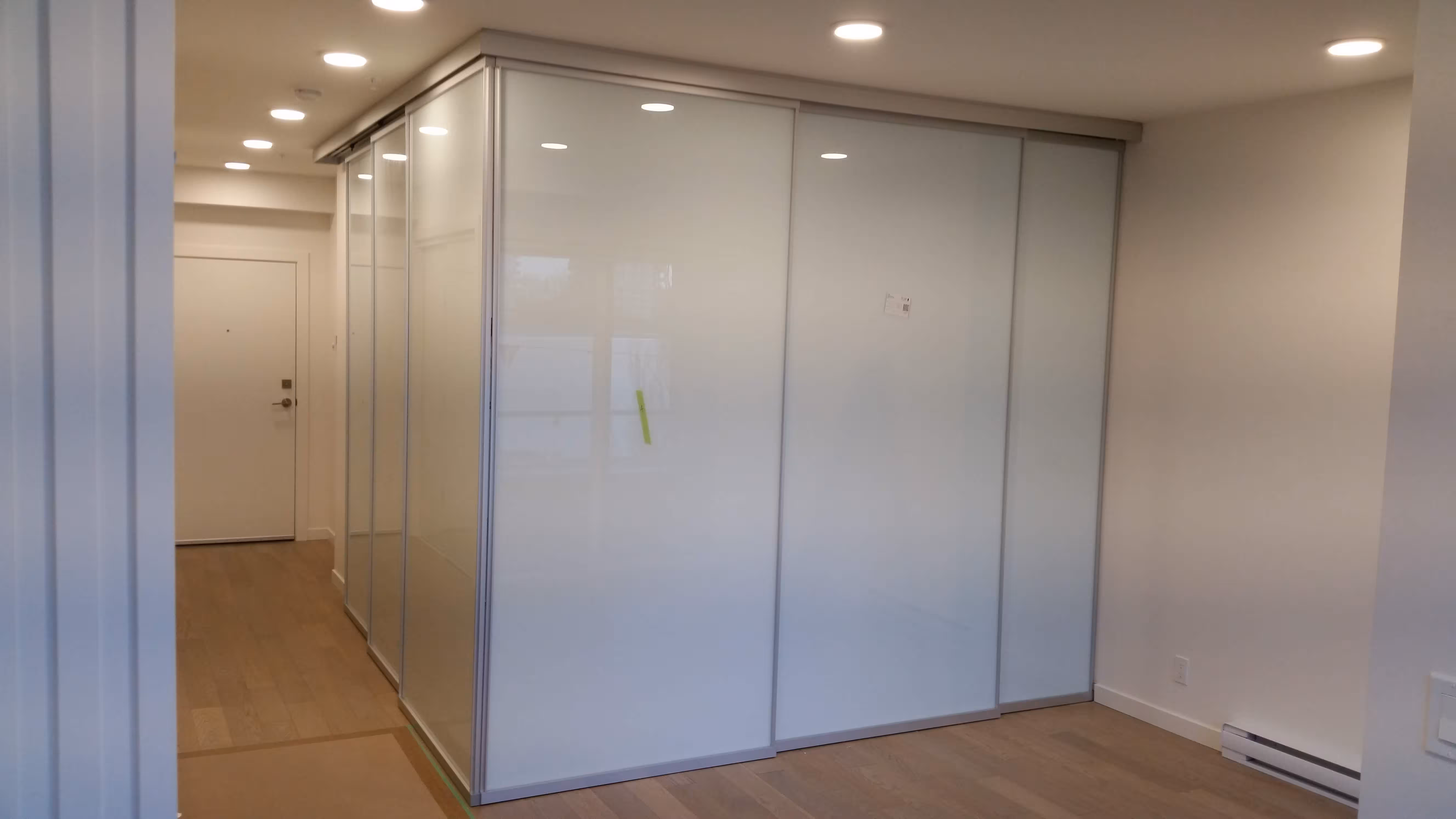 Light oak flooring in a modern entryway with frosted glass sliding panels