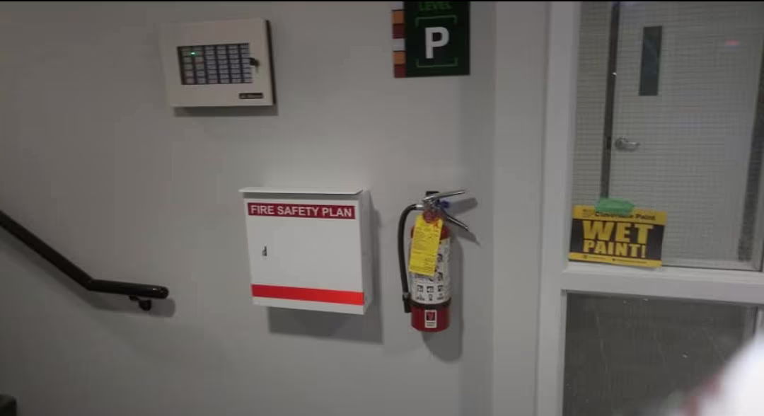 Fire safety plan cabinet and fire extinguisher on a stairwell wall.