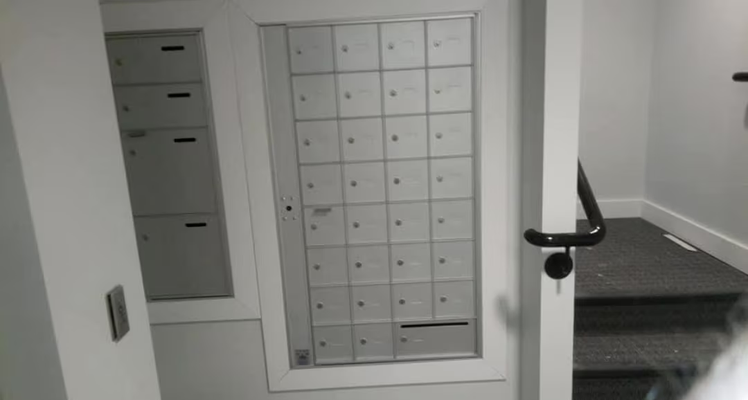 Recessed wall of small mailboxes with larger compartments near a stairwell