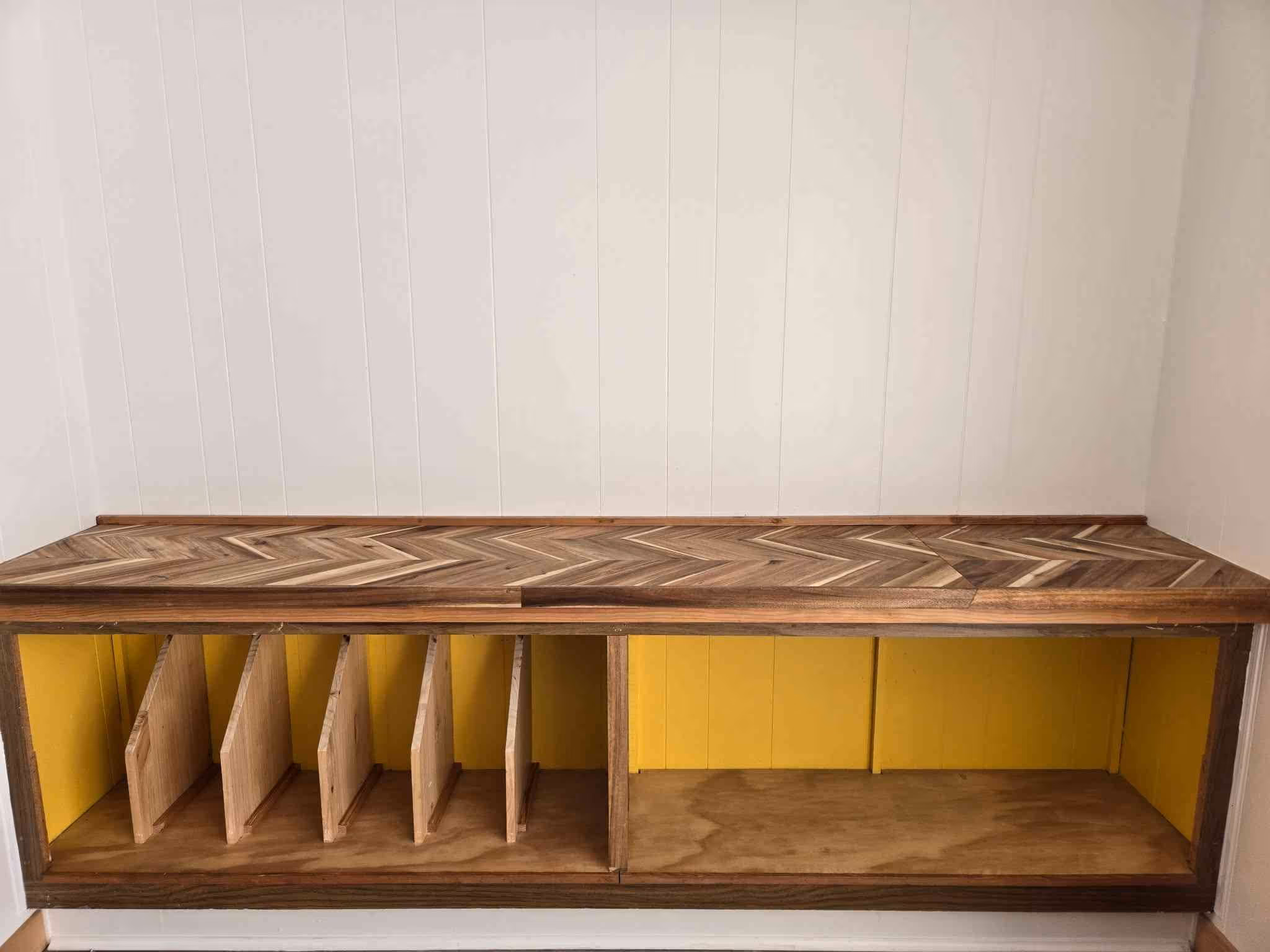 Wood cabinet with herringbone top, yellow cubbies with vertical dividers, and an open shelf.